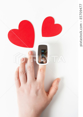 Covid Valentine day concept, hand with pulse oximeter on a finger and a heart symbol 85709477