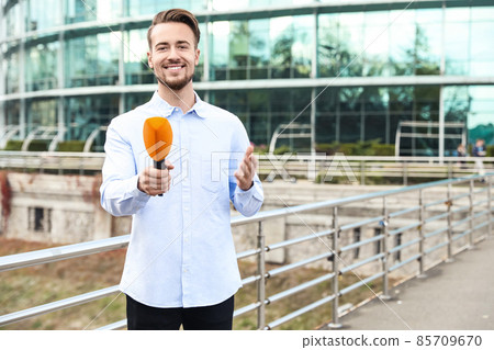 Young male journalist with microphone working on city street. Space for text Young male journalist with microphone working on city street. Space for text 85709670
