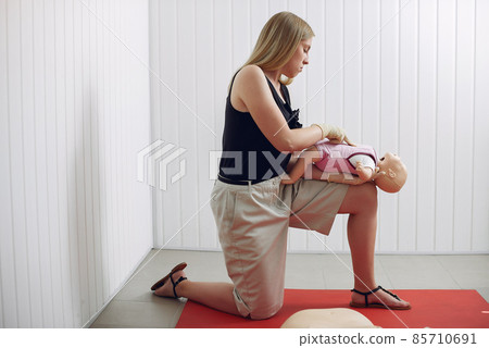 Woman learns to do artificial respiration on a mannequin. Woman learns to do artificial respiration on a mannequin. 85710691
