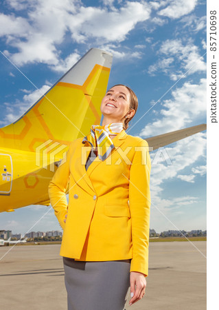 Joyful woman flight attendant standing near plane outdoors 85710698