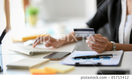 A female banker typing a credit card number on her desktop computer 85715412
