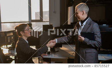 Two young business women shake hands at work. The office staff made a deal Two young business women shake hands at work. The office staff made a deal 85715527