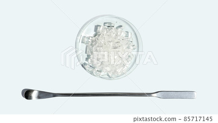 Closeup chemical ingredient on white laboratory table. Sodium Thiosulfate in Chemical Watch Glass placed next to the stainless spatula. Top View Closeup chemical ingredient on white laboratory table. Sodium Thiosulfate in Chemical Watch Glass placed next to the stainless spatula. Top View 85717145