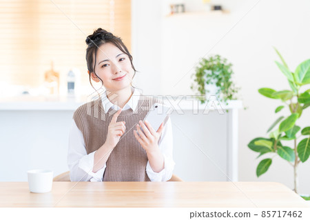 一位在客廳使用智能手機的年輕女子。 85717462