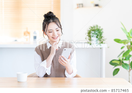 一位在客廳使用智能手機的年輕女子。 85717465