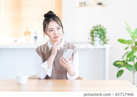 A young woman who uses a smartphone in the living room. A young woman who uses a smartphone in the living room. 85717466