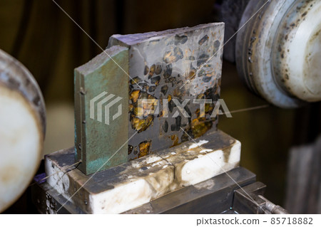 Sawing of the Pallasite iron-stone meteorite with a thin diamond thread. Inclusions of the yellow mineral olivine in a meteorite 85718882