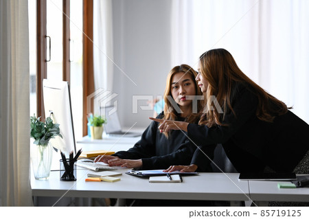 Businesswoman pointing on screen of computer and explaining information to her colleague. Businesswoman pointing on screen of computer and explaining information to her colleague. 85719125