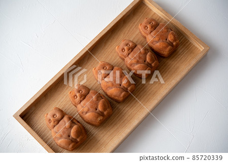 Five raccoon dog ningyo-yaki lined up on a wooden tray 85720339
