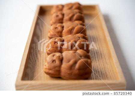 Five raccoon dog ningyo-yaki lined up on a wooden tray 85720340