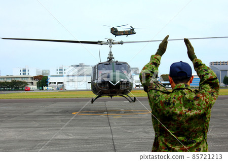 Marshaller issuing takeoff instructions to UH-1 helicopter Marshaller issuing takeoff instructions to UH-1 helicopter 85721213