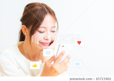 A smiling woman looking at a smartphone A smiling woman looking at a smartphone 85723902