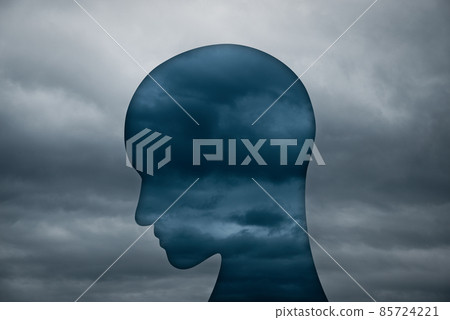 Image of depression and negative emotions. A cloudy sky and a silhouette of a person's head looking down. 85724221