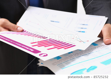 Businessman in suit holding agreement form or annual report in finance Businessman in suit holding agreement form or annual report in finance 85725232