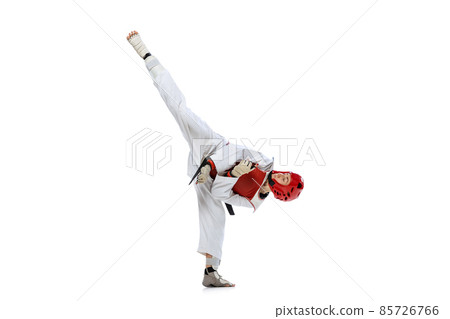 Young girl, taekwondo practitioner strikes forcibly with the foot isolated over white background. Concept of sport, skills 85726766