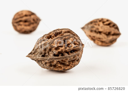 three walnuts lie separately on a white background. focus on the near nut three walnuts lie separately on a white background. focus on the near nut 85726820