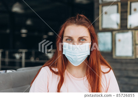 A happy woman in a protective medical mask on her face sits at the airport waiting for a flight A happy woman in a protective medical mask on her face sits at the airport waiting for a flight 85726855