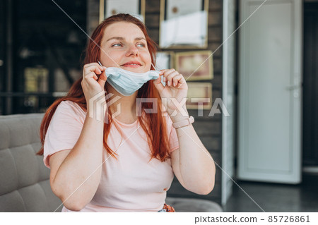 Happy woman takes off protective mask indoors while corona virus pandemic. Quarantine, and social distance concept. Girl waiting for a flight Happy woman takes off protective mask indoors while corona virus pandemic. Quarantine, and social distance concept. Girl waiting for a flight 85726861