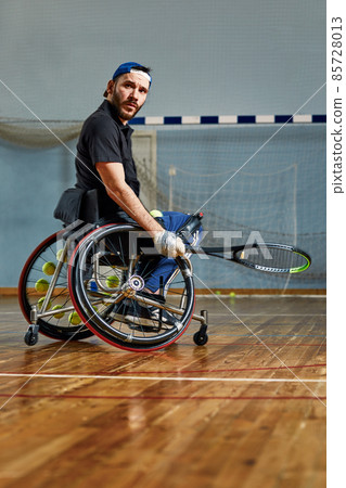Young man in wheelchair playing tennis on court. Wheel Chair Tennis. Young man in wheelchair playing tennis on court. Wheel Chair Tennis. 85728013