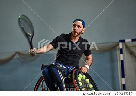 young man with a physical disability playing tennis on wheelchair on tennis court 85728014