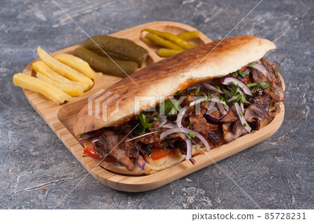 Turkish Doner with veal in a pit with French fries, pickles and red onions Turkish Doner with veal in a pit with French fries, pickles and red onions 85728231