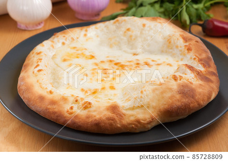 Khachapuri Megrelian Georgian cuisine on a dark plate Khachapuri Megrelian Georgian cuisine on a dark plate 85728809