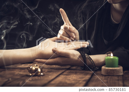 A fortune teller or oracle in search of the lines of fate in the palm of a person. Fortune telling by hand, predicting the future 85730181