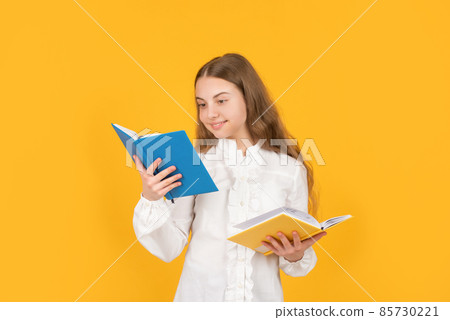 cheerful child reading school book on yellow background, school 85730221