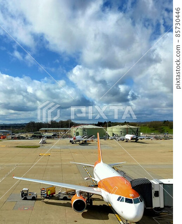 等待乘客的客機在春天的白雲下倫敦蓋特威克機場 85730446