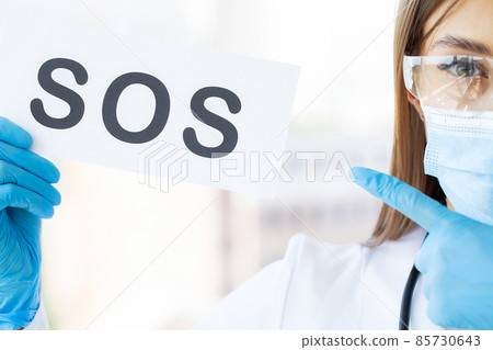 Young doctor in protective mask and gloves holding sos sign 85730643
