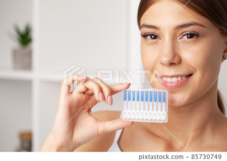 The woman uses brushes to clean the interdental spaces 85730749