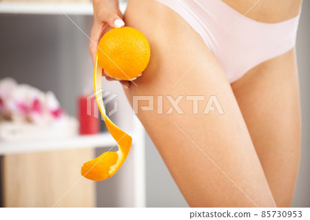 Woman with an orange showing a perfect skin without cellulitis 85730953