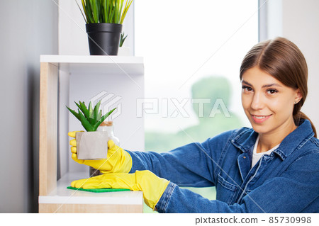 Pretty woman in uniform with supplies cleaning in office 85730998