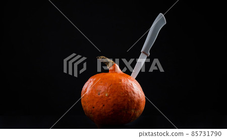 Knife in a pumpkin on a black background. Halloween symbol. Isolate. 85731790
