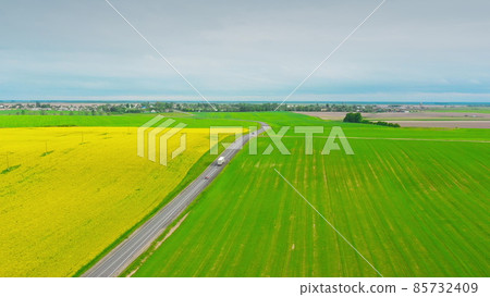 Aerial View Of Highway Road Through Field And Summer Wheat Fields Landscape. Top View Of Truck Tractor Unit Prime Mover Traction Unit In Motion On Freeway. Business Transportation, Trucking Industry Aerial View Of Highway Road Through Field And Summer Wheat Fields Landscape. Top View Of Truck Tractor Unit Prime Mover Traction Unit In Motion On Freeway. Business Transportation, Trucking Industry 85732409
