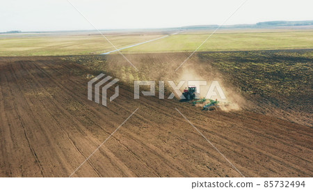 4K Aerial Elevated View.Tractor Plowing Field. Beginning Of Agricultural Spring Season. Cultivator Pulled By A Tractor In Countryside Rural Field Landscape 85732494