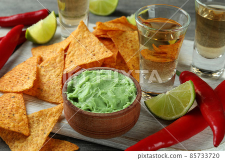 Party concept with tequila, guacamole and chips Party concept with tequila, guacamole and chips 85733720