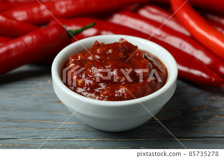 Red chili peppers and sauce on gray wooden background 85735278