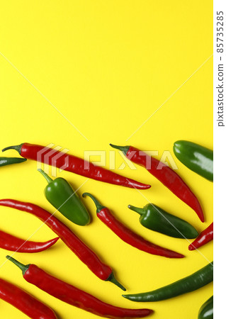 Red and green hot peppers on yellow background 85735285