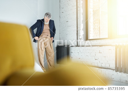 Full length shot of stylish middle aged man in business casual wear putting hands in pockets while posing against white background in loft interior 85735395