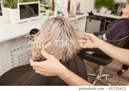 Male hairdresser serving young woman in beauty salon 85735412