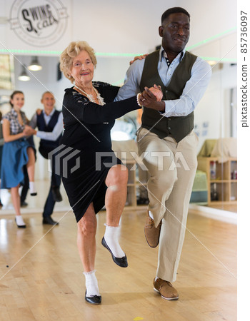 Woman pensioner with african man practising charleston Woman pensioner with african man practising charleston 85736097