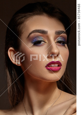Naked model in necklace and earrings posing on gray background. Bright makeup, perfect skin. Colorful eyeshadow, long eyelashes, red lips. Close up Naked model in necklace and earrings posing on gray background. Bright makeup, perfect skin. Colorful eyeshadow, long eyelashes, red lips. Close up 85736488