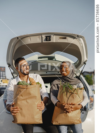 Diverse couple with grocery at car trunk 85736686