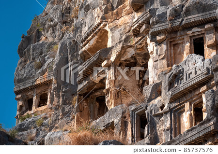 fragment of famous complex of rock tombs in the ruins of Myra of Lycia with reliefs on the cliff 85737576
