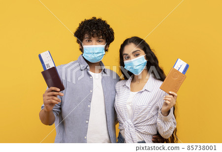 Young indian couple wearing protective face masks, holding passports and flight tickets 85738001