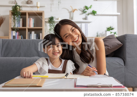 Happy asian young mother smile with daughter in living room at home. Asian young mother teaching small daughter to drawing reading and writing to develop her daughter skill. Home School Concept 85738074