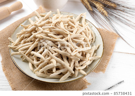 Whole grain wheat raw apulian pasta called Pizzarieddi or maccaruni on a ceramic plate on white wooden table Whole grain wheat raw apulian pasta called Pizzarieddi or maccaruni on a ceramic plate on white wooden table 85738431
