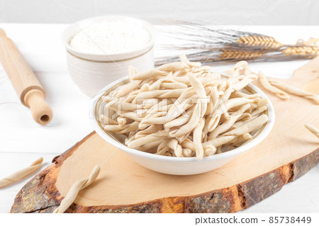 Whole grain wheat raw apulian pasta called Pizzarieddi or maccaruni on a ceramic plate on white wooden table 85738449