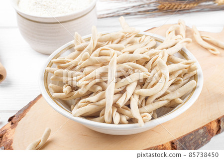 Whole grain wheat raw apulian pasta called Pizzarieddi or maccaruni on a ceramic plate on white wooden table 85738450